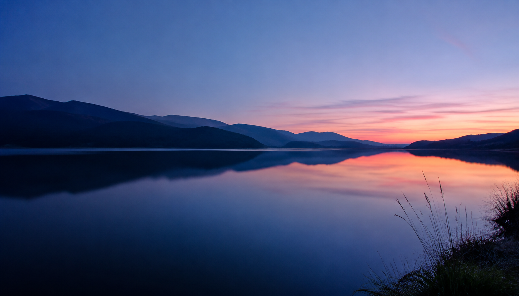 Still lake water between mountains at sunset